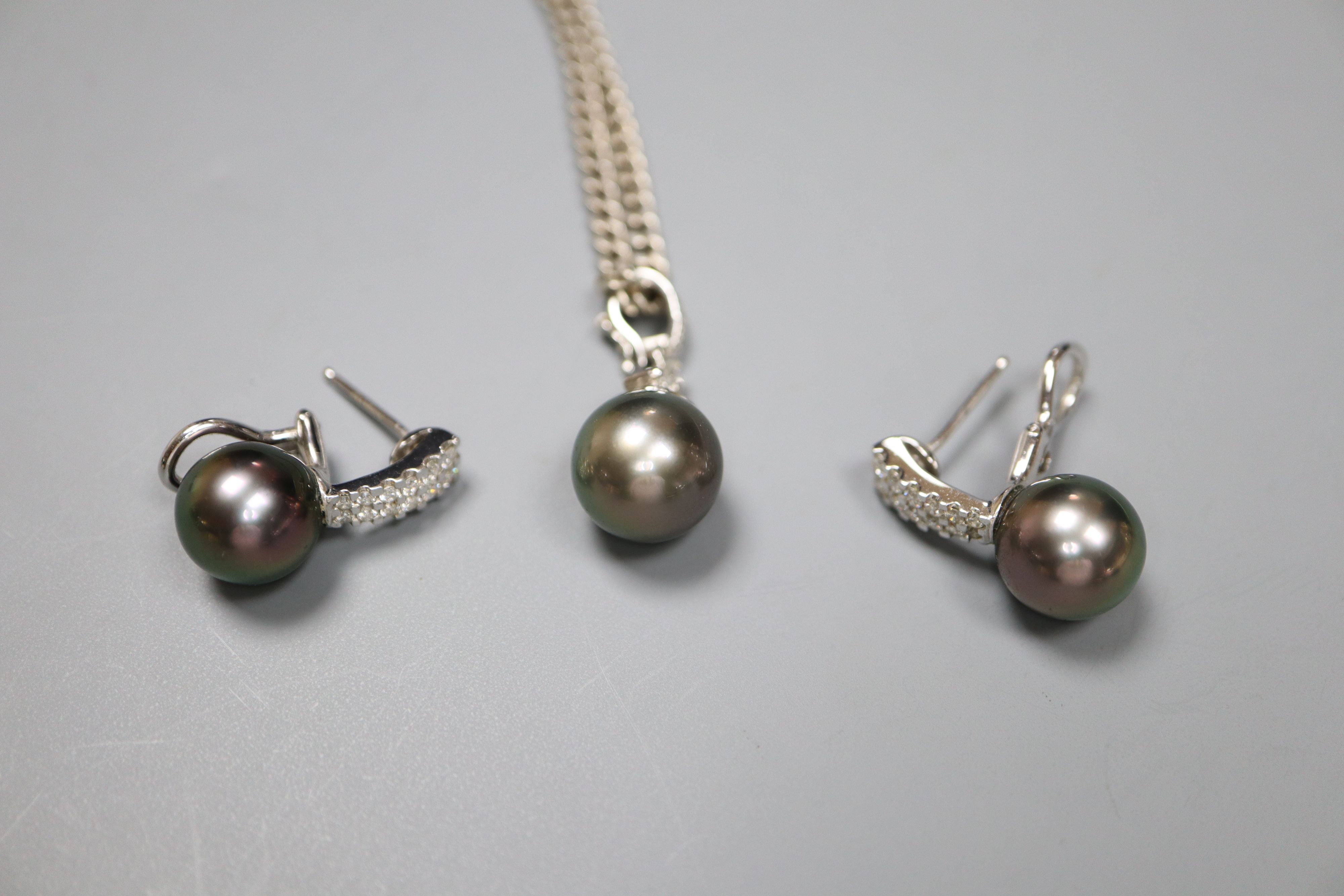 A modern 18k white metal , cultured Tahitian? pearl and diamond set pendant and pair of matching earrings.
